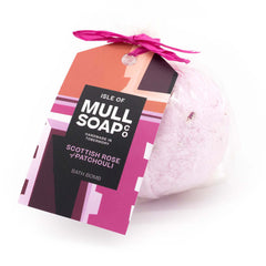 pink coloured round Scottish rose and patchouli bath bomb presented as a gift in a bag with coloured tag and bow. decorated with rose petals. Handmade by the Isle of Mull soap co in Tobermory, Scotland.