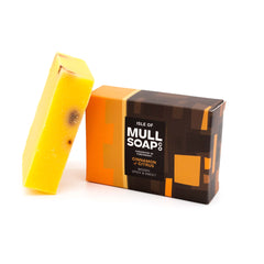 a cinnamon and citrus soap box sitting next to the soap bar. The box is a a brown and orange design. The soap is described as woody, spicy and sweet. Handmade in Tobermory by the Isle of Mull soap co.