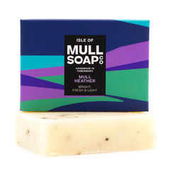 a mull heather soap box sitting on a soap bar. The box is a purple and green rolling hills design. The soap is described as bright, fresh and light. Handmade in Tobermory by the Isle of Mull soap co.
