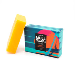 an orange and patchouli box sitting next to the soap bar. The box is blue with a bright orange buoy design. The soap is described as warm and juicy. Handmade in Tobermory by the Isle of Mull soap co.