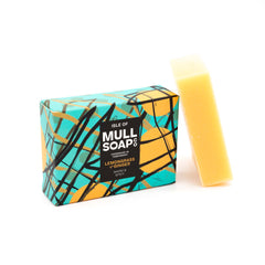 a lemongrass and ginger soap box sitting next to the soap bar. The box design is green with yellow buoys and black fishing nets. The soap is described as warm and spicy. Handmade in Tobermory by the Isle of Mull soap co.